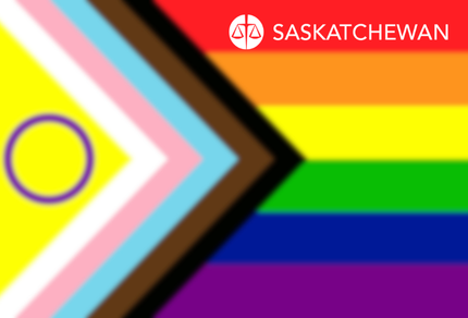 Progress pride flag waving in the wind against a blue sky